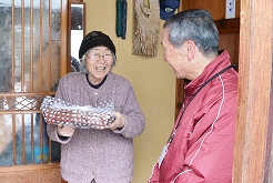 おせち料理を配布する様子。右が民生児童委員の小柴正意さん