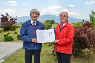 署名した協定書を掲げる辰野代表取締役会長と薄町長